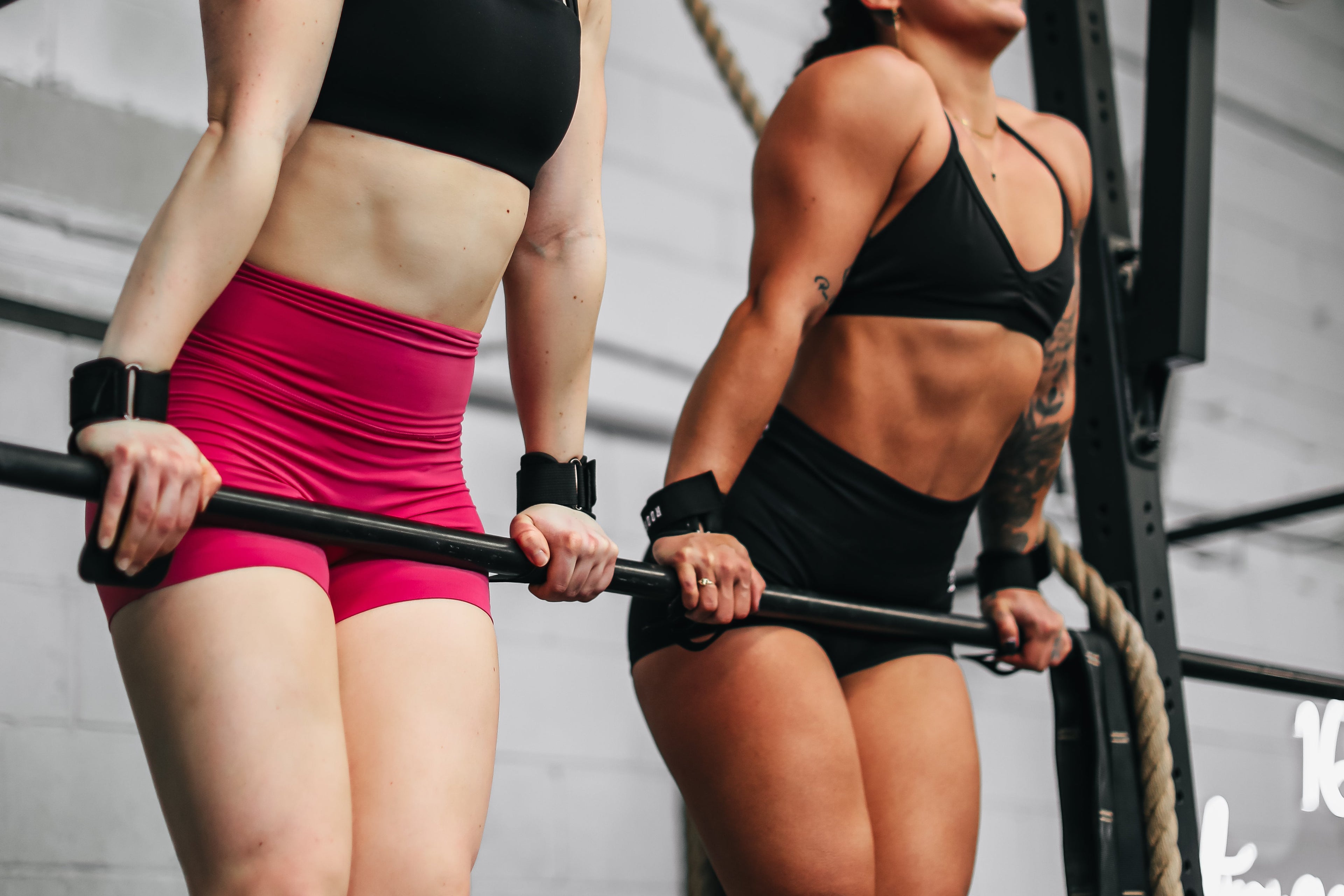 Two women exercising with a barbell in a gym setting