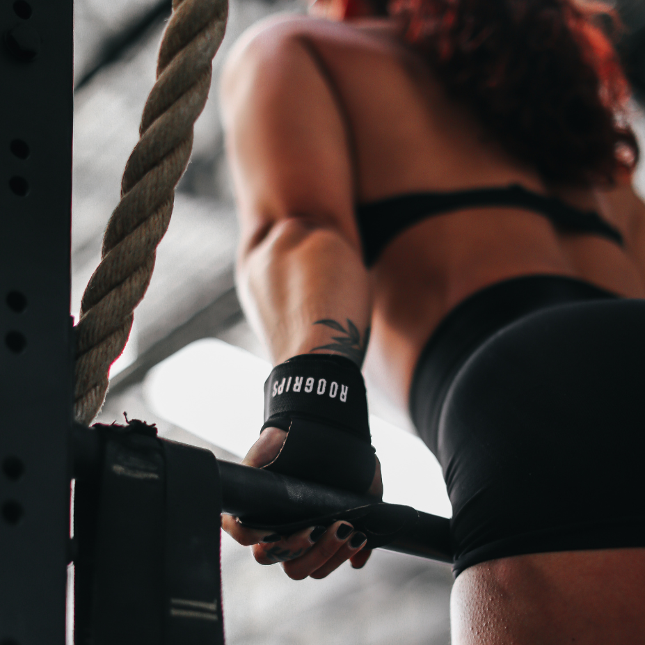 Person performing pull-ups on a barbell in a gym setting